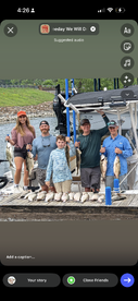 A family group proudly displaying their catch of striped bass on the dock after a successful fishing trip.