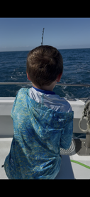 A young angler is focused on fishing from the boat, enjoying a day on the open water.