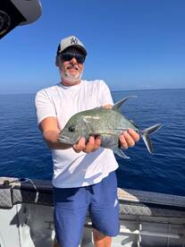 Angler proudly displaying a Grey Snapper while fishing in clear blue waters.