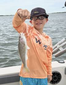 A young angler proudly displaying a caught fish while fishing from a boat, showcasing a fun day on the water.