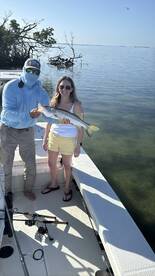 Anglers proudly displaying a Snook caught during a sunny day on the water, showcasing a fun fishing experience.