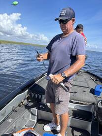 Angler actively reeling in a fish while fishing from a boat in a scenic waterway, showcasing a vibrant fishing environment.