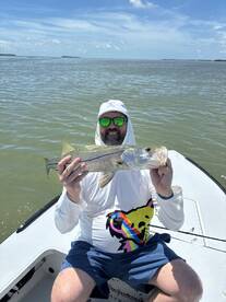 Angler proudly displaying a Snook while fishing on a sunny day in coastal waters.