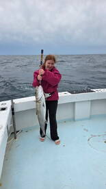 A young angler proudly holding a large fish on a fishing charter in open waters.