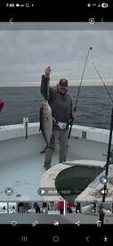 Angler proudly displaying a large fish on the deck of a fishing boat during an offshore trip.