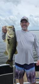 Angler proudly displaying a large Largemouth Bass while fishing on a lake, showcasing a successful day on the water.