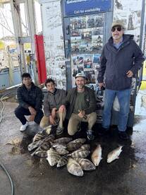 A family group proudly displaying their catch of various fish, including Black Drum and Sheepshead, at a Galveston fishing dock.