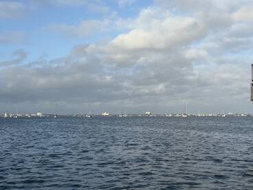 A scenic view of the water with sailboats in the distance, capturing the tranquil atmosphere of a fishing environment.