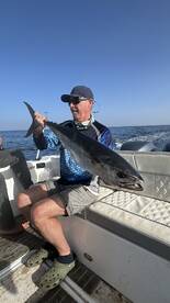 Angler proudly displaying a large fish while seated on a boat, enjoying a day of offshore fishing.