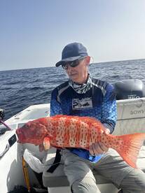Angler displaying a vibrant Red Grouper while fishing offshore, showcasing the excitement of a successful catch.