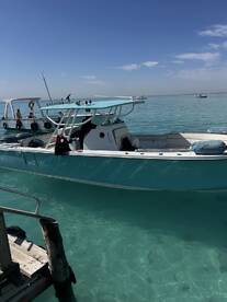 A vibrant fishing boat named 'Poseidon' docked in clear turquoise waters, showcasing a sunny day in a tropical fishing environment.