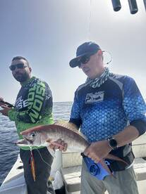 Two anglers proudly displaying a large Snapper caught during a deep-sea fishing trip.
