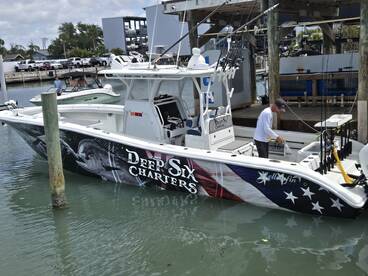 The 'Deep Six Charters' boat is docked, showcasing its striking design with an American flag theme and fishing gear on board.