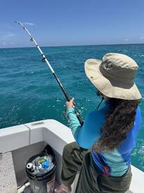 A young angler is actively fishing from a boat in clear blue waters, showcasing the excitement of the fishing experience.