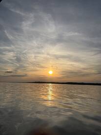 A serene sunset over calm waters, reflecting the vibrant colors of the sky, creating a picturesque fishing environment.