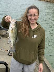 A young angler proudly displaying a large Largemouth Bass while fishing from a boat.