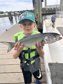 A young angler proudly displaying a caught fish while standing on the dock, showcasing a fun fishing experience.