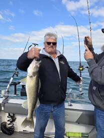 Angler proudly displaying a large Walleye while fishing on a boat, showcasing a successful day on the water.