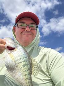 Angler proudly displaying a Crappie while enjoying a sunny day on the water.
