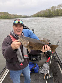 Angler proudly displaying a large Smallmouth Bass while fishing on a river, showcasing a successful day on the water.