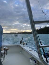 A scenic view from the helm of a fishing boat, showcasing the tranquil waters and another vessel in the distance during a fishing trip.