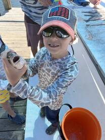 A young angler proudly displaying a fish at the dock, showcasing a fun family fishing experience.