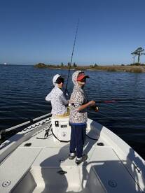 Two young anglers fishing from a boat in calm waters, showcasing a fun day on the water.