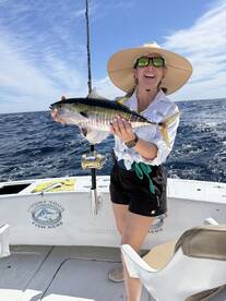 Angler proudly displaying a vibrant Yellowfin Tuna while fishing on a sunny day at sea.