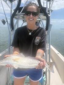 Angler proudly displaying a freshly caught Snook while aboard a fishing boat in calm waters.