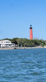 A scenic view of a red lighthouse and waterfront property, showcasing the coastal environment near a fishing area.