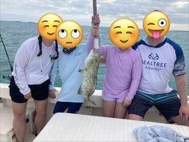 Family enjoying a successful fishing trip, proudly displaying a large Grouper caught in the open waters.