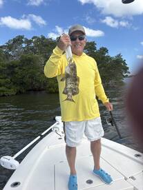 An angler proudly displaying a large grouper while fishing from a boat in a scenic coastal environment.