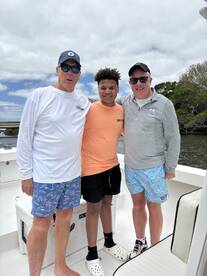 Three anglers posing together on a boat, enjoying a fishing trip.