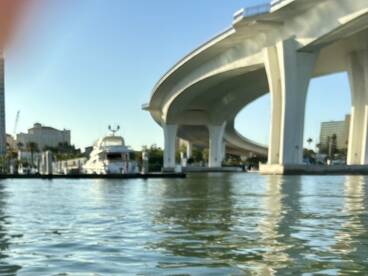 A scenic view of a luxury yacht docked under a bridge, showcasing the urban waterfront environment.