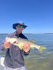 Angler proudly displaying a Snook while fishing in a scenic coastal environment.