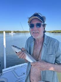 An angler proudly displaying a Speckled Trout while fishing from a boat in a serene coastal environment.