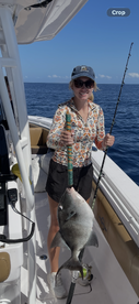 A proud angler holding a large fish on a fishing boat in open waters, showcasing a successful day of fishing.