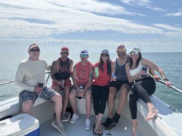 A group of six friends enjoying a sunny day on a boat, showcasing a relaxed atmosphere on the water.
