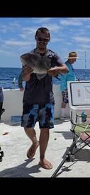 Angler proudly displaying a large fish on a fishing charter in open waters, showcasing a vibrant day of fishing.