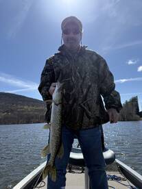 Angler proudly displaying a Northern Pike while fishing on a scenic lake, showcasing the thrill of freshwater fishing.