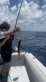 A young angler reeling in a fish while fishing on a boat in open water, showcasing the excitement of the catch.