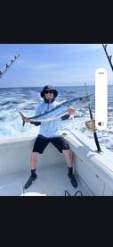 Angler proudly displaying a large Wahoo while fishing offshore, showcasing a successful day on the water.