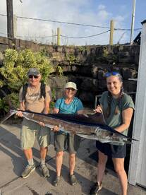 A family proudly displays a large Sailfish caught during their fishing trip, showcasing their successful catch at the dock.