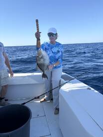 An angler proudly displaying a large Snapper while fishing on a boat in open waters.