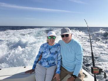 A couple enjoying a day on the water, seated on the boat with a scenic ocean backdrop.