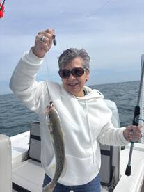 A smiling angler proudly displaying a freshly caught fish while fishing on a boat, showcasing a fun day on the water.