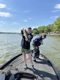 A happy angler proudly displaying a large Largemouth Bass while fishing on a Ranger boat, enjoying a sunny day on the water.