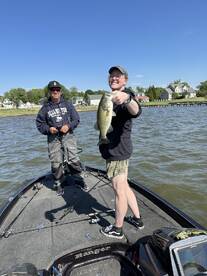 A young angler proudly displays a large Largemouth Bass while fishing on a Ranger boat, enjoying a sunny day on the water.