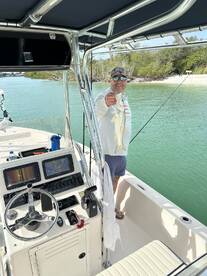 Angler proudly displaying a Snook while aboard a center console boat in a scenic coastal waterway.