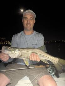 Angler proudly displaying a large Snook while fishing at night, showcasing the excitement of a successful catch.